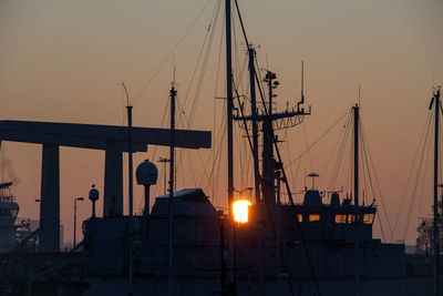 Silhouette sailboats moored on harbor against sky during sunset