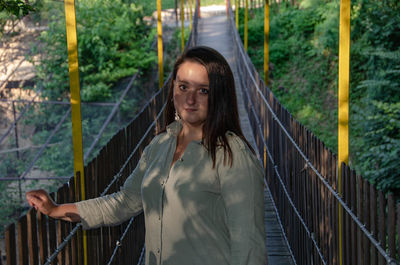 Portrait of young woman standing by railing