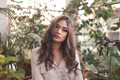 Portrait of young woman sitting against plants