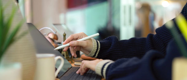 Midsection of man using mobile phone while sitting on table