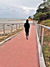 Rear view of man walking on footpath