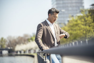 Man looking away while standing against railing