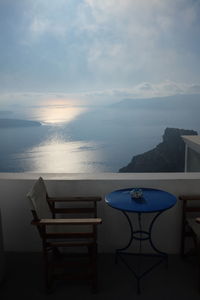 Chairs and tables at restaurant by sea against sky