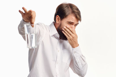 Young man holding stinking water against white background