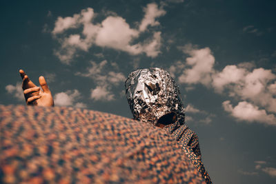 Low section of person holding umbrella against sky