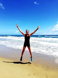 Full length of young woman at beach against sky