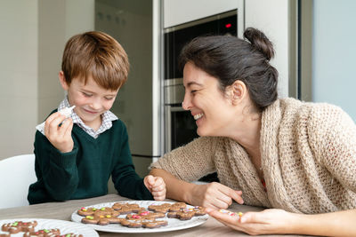 Mother and son preparing food on table at home