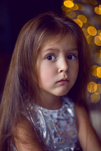 Baby girl sitting in studio in dress with christmas tree in christmas with long hair