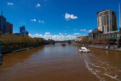 Boats in river by city against sky