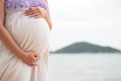 Midsection of woman touching tree