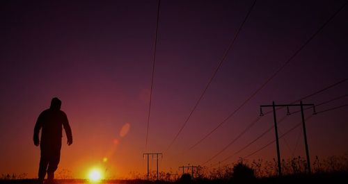 Rear view of silhouette man standing against sky during sunset