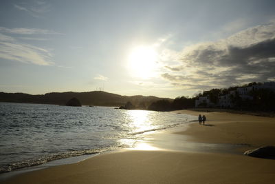 Silhouette person on beach against sky during sunset