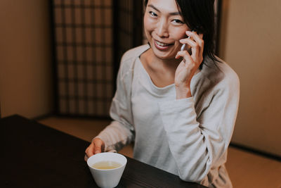 Mid adult woman using mobile phone while sitting on table