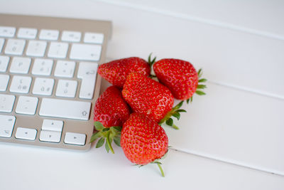 Computer keyboard and strawberries on table