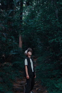 Full length of young woman standing in forest