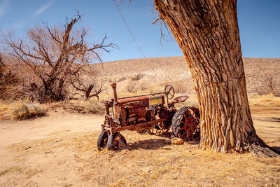 Bicycle parked on tree trunk on field against sky