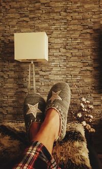 Low section of woman wearing shoes on brick wall