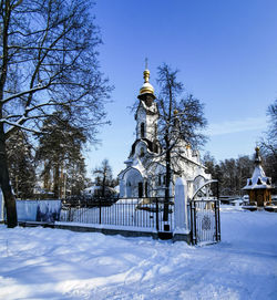 Gazebo by building against sky during winter