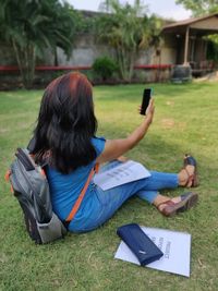 Woman using mobile phone while sitting on field