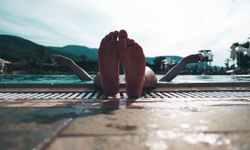 Low section of man in swimming pool against sky