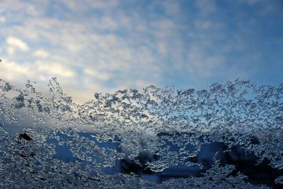 Close-up of frozen water against blue sky