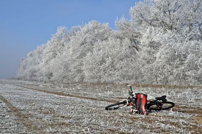 Bicycle on field against sky during winter