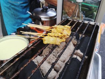 Close-up of person preparing food on barbecue grill