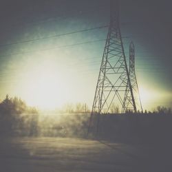 Power lines against sky at sunset