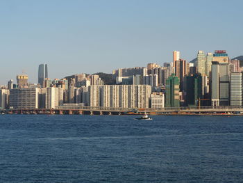 Sea by cityscape against clear sky
