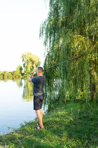 The guy throws a fishing rod against the backdrop of the lake. the concept of relaxation and hobby