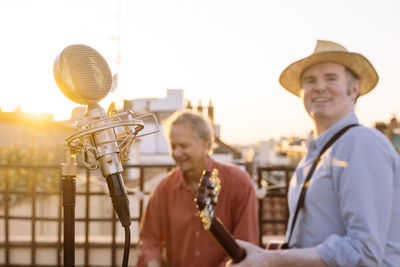 Portrait of man holding guitar standing outdoors