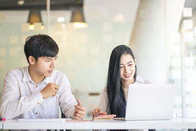 Young colleagues discussing at desk in office