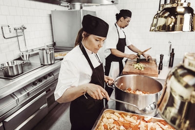 Kvinnlig kock förbereder plåt i restaurangkök