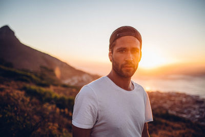 Portrait of young man standing against sky during sunset