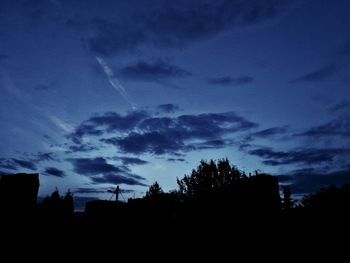 Silhouette of trees against cloudy sky