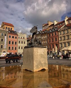 Statue by buildings in city against sky