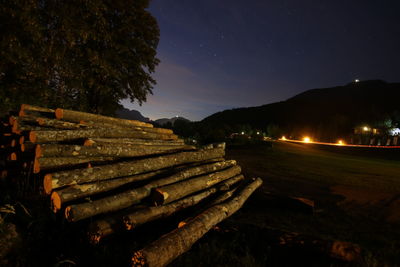 Stack of logs on field against sky at night