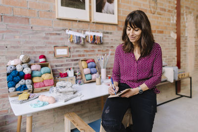 Smiling woman in knitting studio taking notes