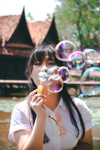 Portrait of woman blowing bubbles outdoors