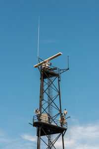 Military coastal surveillance radar station against blue sky.