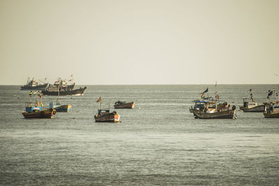 Boats sailing in sea against clear sky