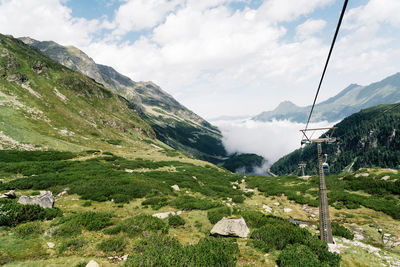 Overhead cable car on mountains against sky