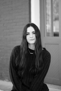 Portrait of smiling young woman standing against wall