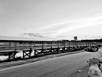 Road by bridge in city against sky