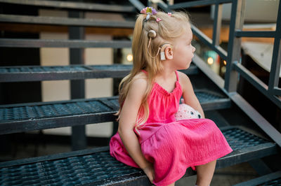 Portrait of young woman sitting on railing