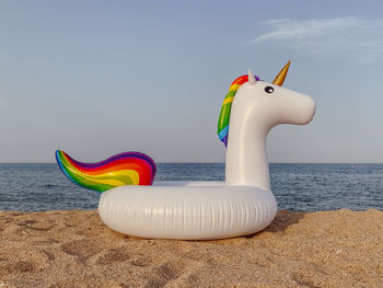 Stuffed toy on beach against sky