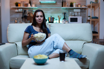 Portrait of young woman sitting on sofa at home