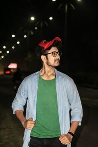 Portrait of young man standing against illuminated wall