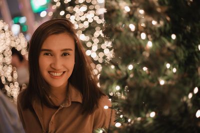 Portrait of smiling young woman with christmas tree