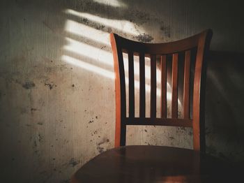 Empty chair by table against wall at home